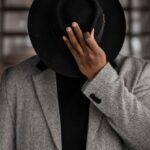 Gender-Neutral Fashion - Person in Gray Coat Holding Black Hat