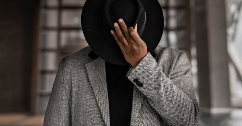 Gender-Neutral Fashion - Person in Gray Coat Holding Black Hat