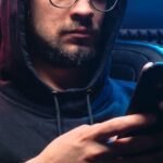 Data Breaches - A Man in Black Hoodie Sweater Using His Mobile Phone