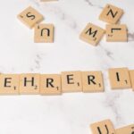 Mentorship - Scrabble tiles spelling lehrerin on a white marble surface